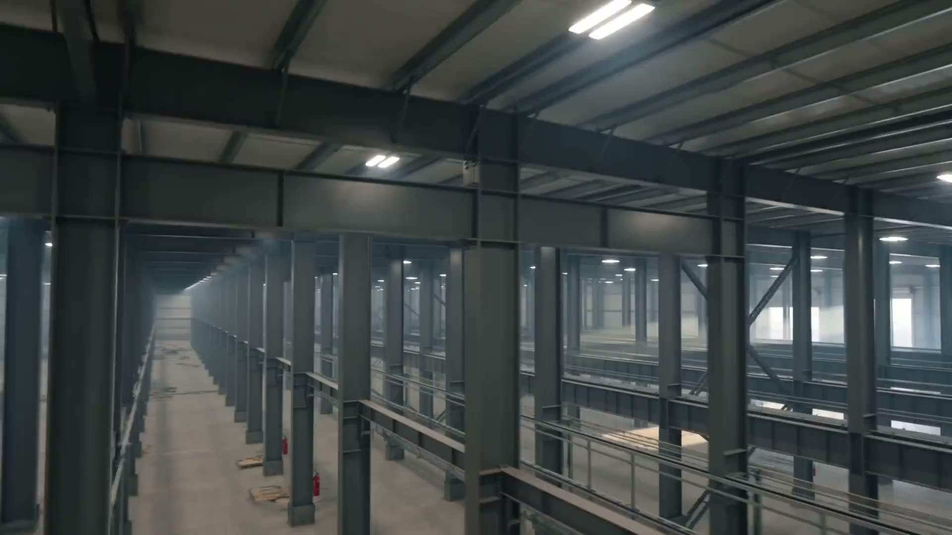 The interior of a steel-frame commercial building at the electrical fit-out stage, fixtures burning along the deck