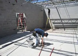 Electrician working at floor level inside a commercial shell