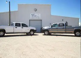 Two white Baker Electric service trucks parked at the shop on Frankford Avenue