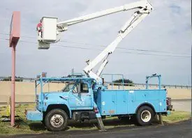 An older blue Baker Electric bucket truck still in service on a job